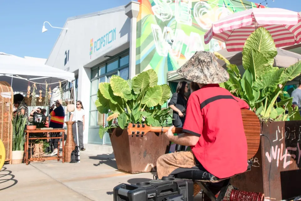 Musician playing guitar in front of outdoor seating and sidewalk vendors in Houston, Texas